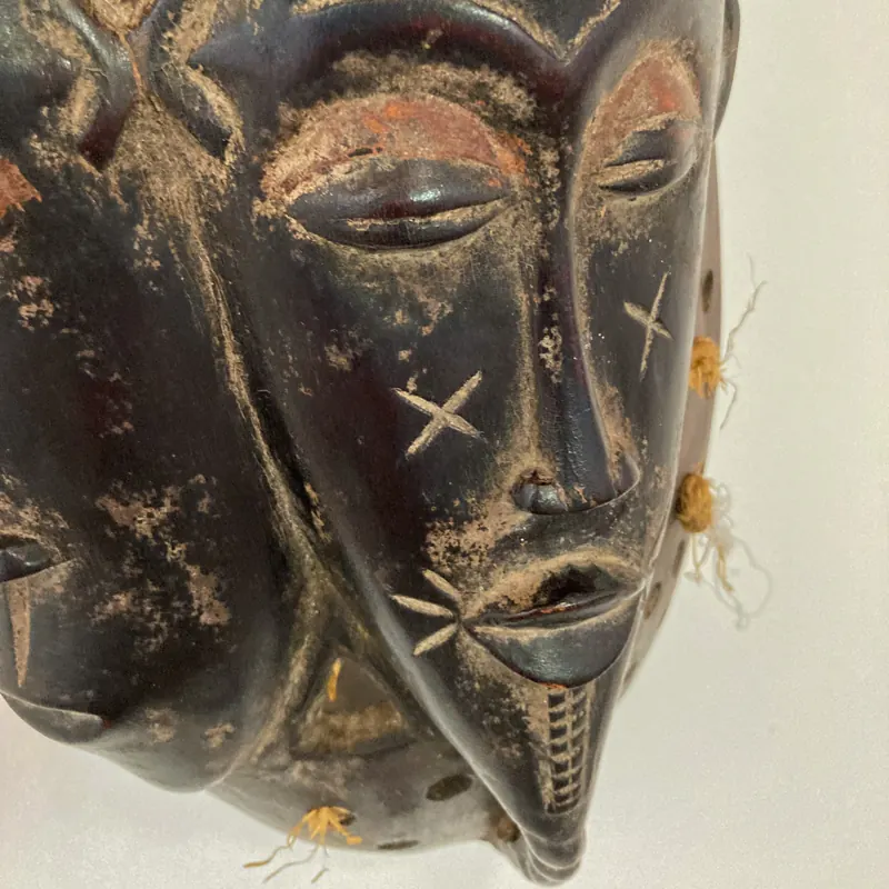 Dark carved mask with incised markings