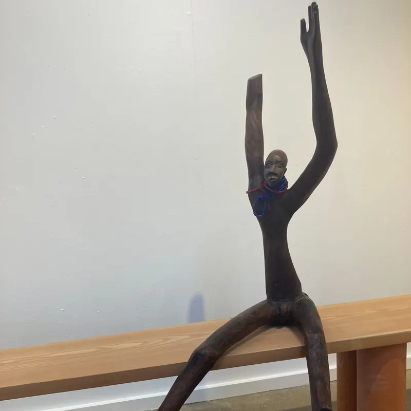 Slender carved figure with arms raised