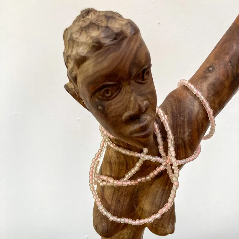 Carved figure wearing strings of beads