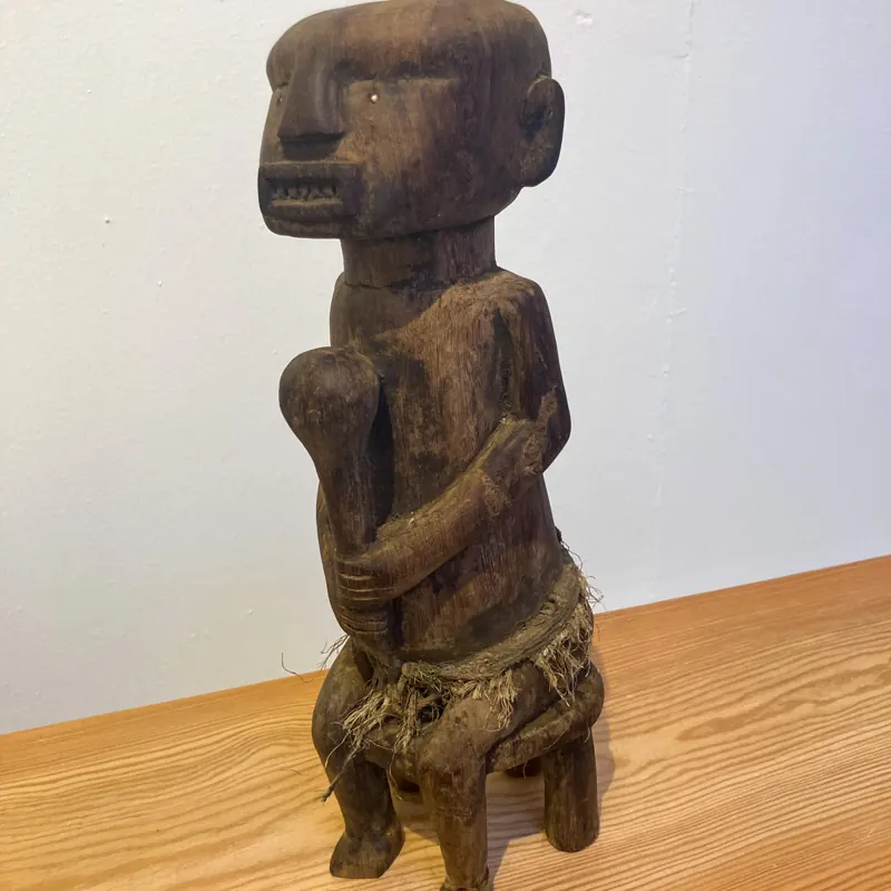 Carved seated figure on a low stool