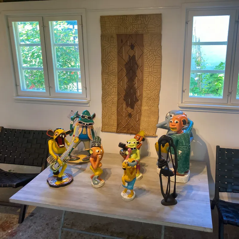 Painted carvings on a table in front of a raffia hanging