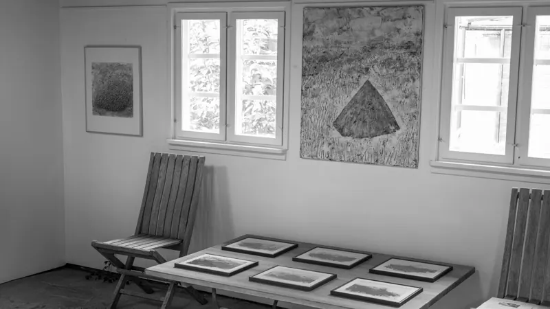 Gallery room with framed works laid on tables beneath the windows