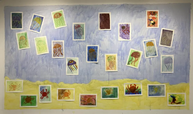 Children’s drawings of crabs and jellyfish on a painted sea and sand background
