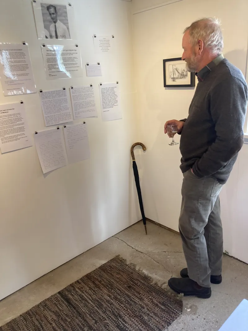 A visitor leaning in to read a label beside a walking stick