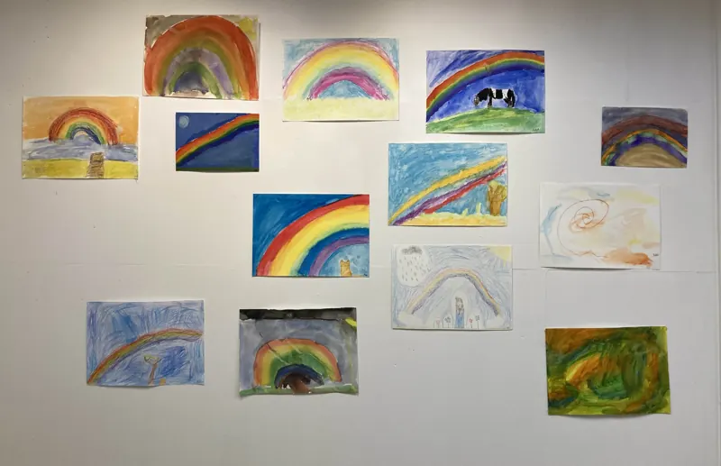 Children’s rainbow paintings pinned to the wall
