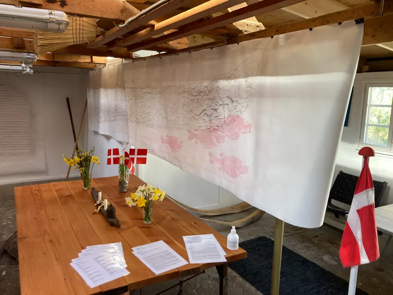 Hanging graphite rubbing above a table set for the opening