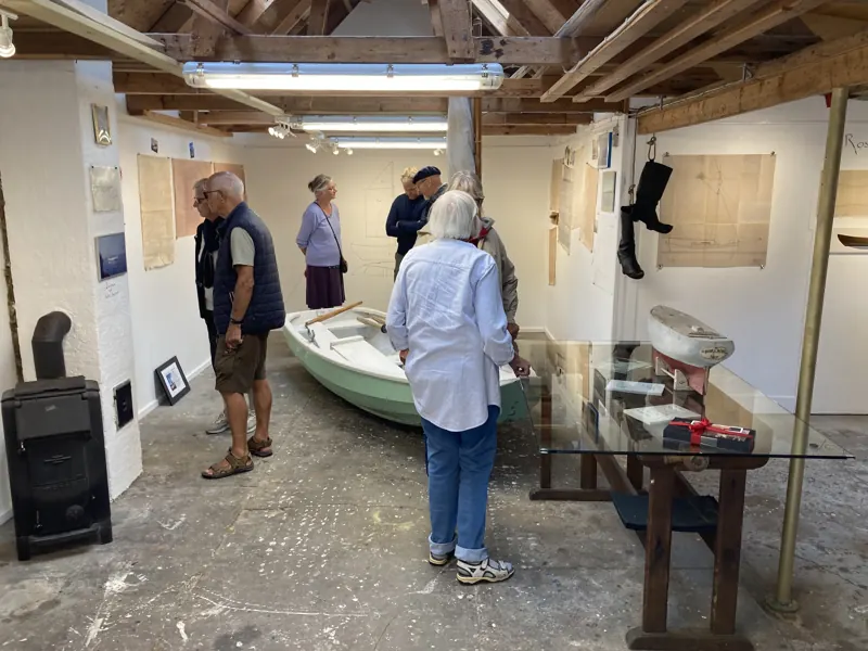 Visitors walking among the exhibits, a white dinghy in the centre