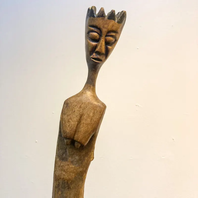 Tall slender carved figure with a crested head