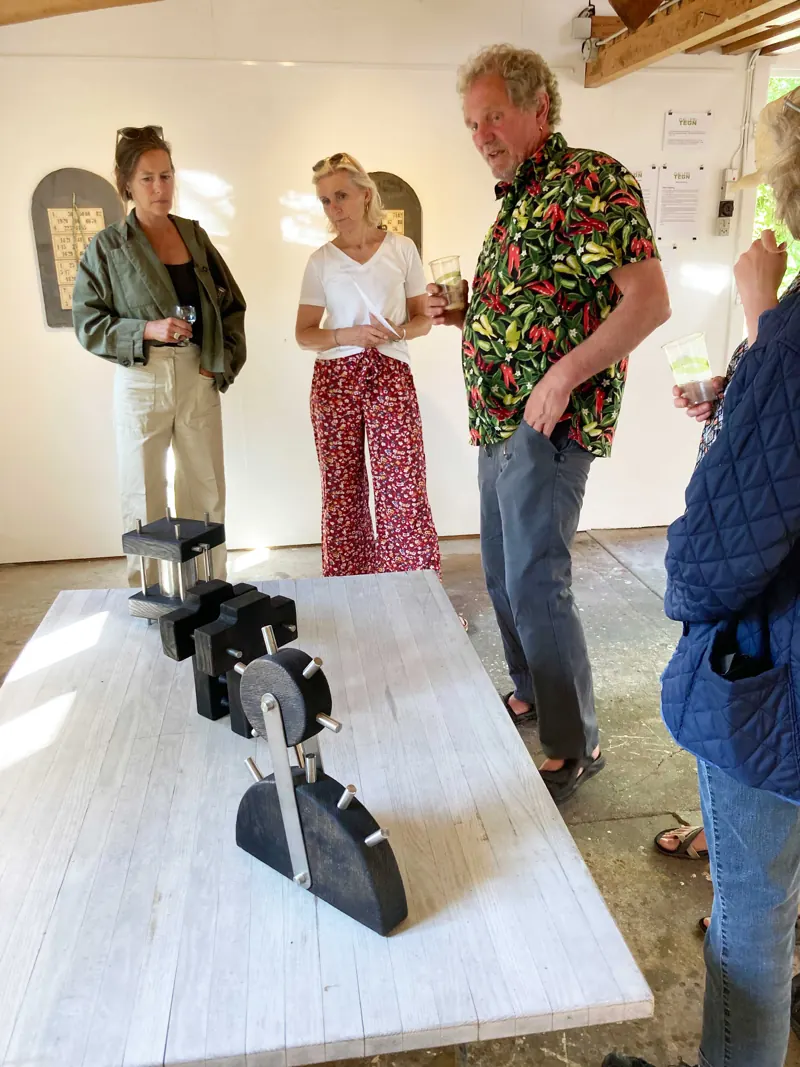 Visitors at the opening around a sculpture on a white table