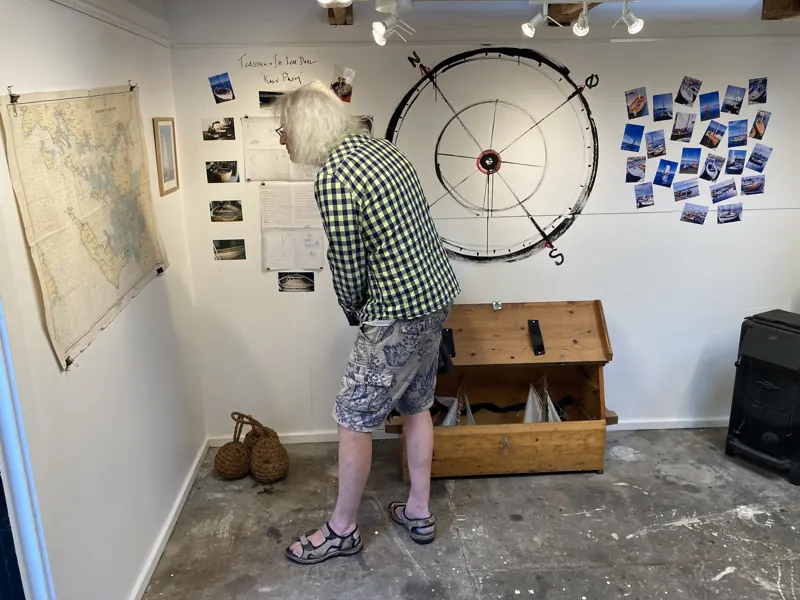 A visitor studying photographs beside a large ship’s wheel