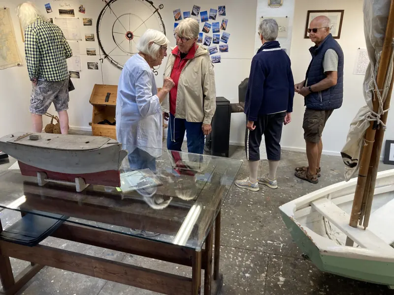 Visitors looking at boat models and a ship’s wheel