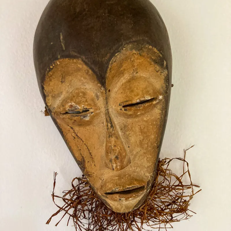 Carved wooden mask with a raffia beard