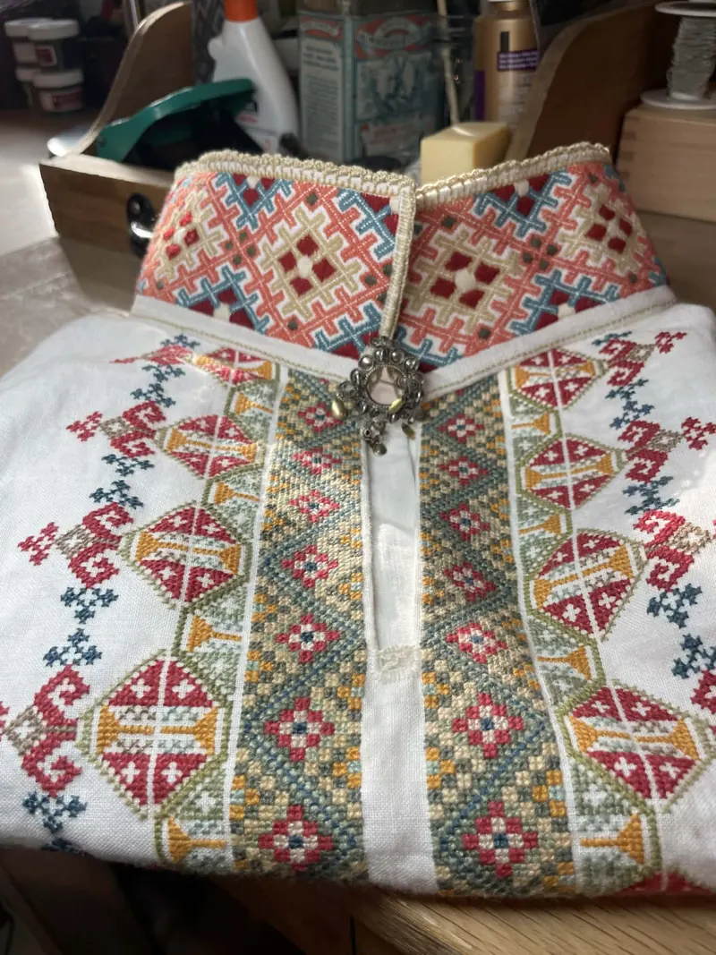 White shirt with dense red and green cross-stitch embroidery