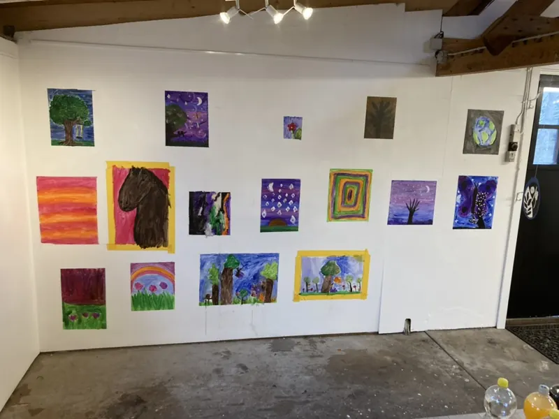 A wall of children’s bright tree and animal paintings