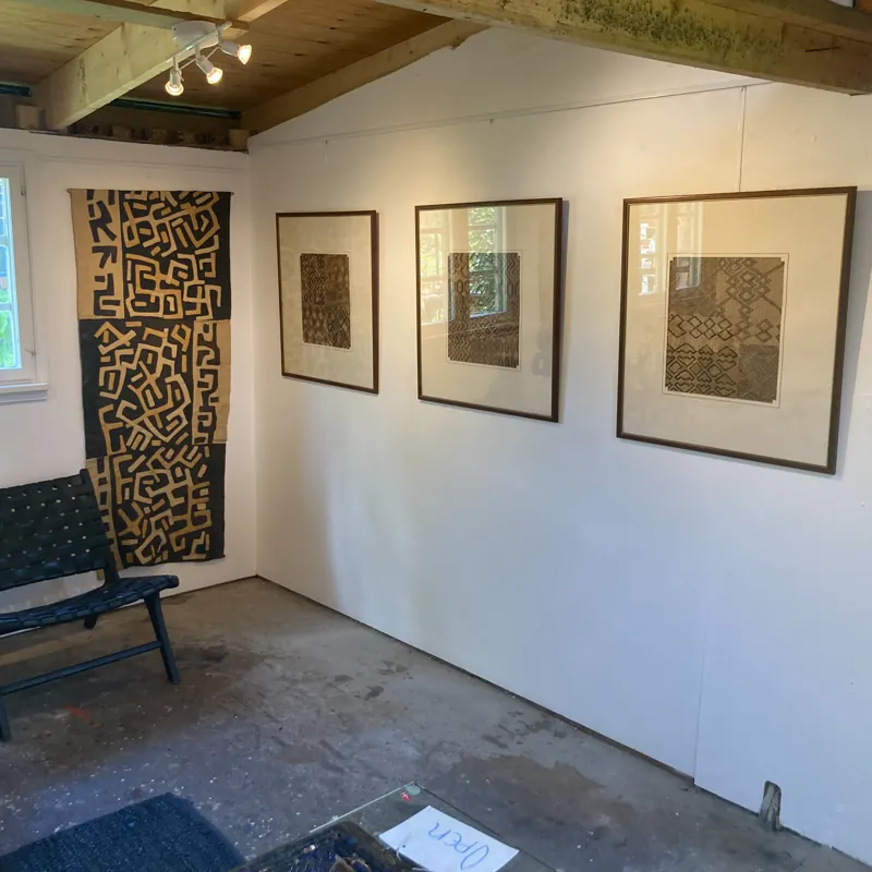 Gallery room with a tall textile hanging and framed textiles