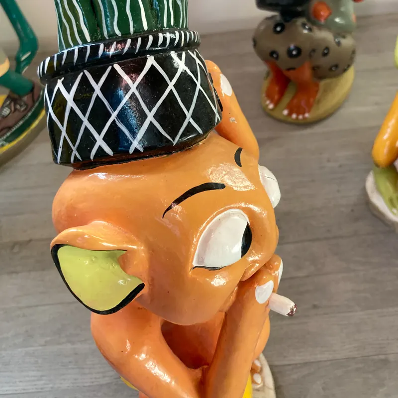 Painted carving of an orange figure in a patterned hat
