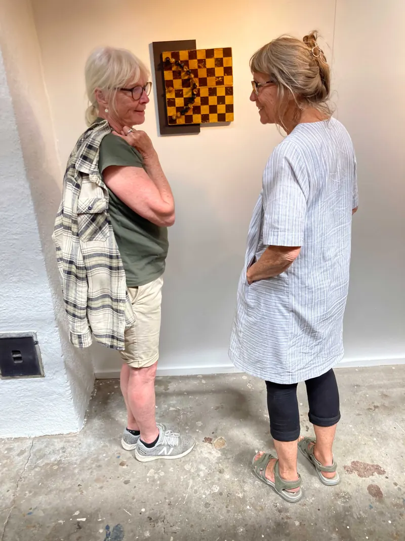 Two visitors talking in front of a framed chequerboard